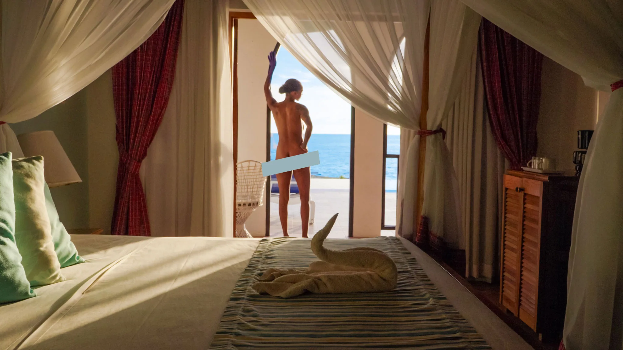 Guest opening bedroom curtains toward the ocean at Le Mirage in Negril