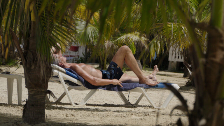 Beach loungers shaded by palms at Charela Inn in Negril