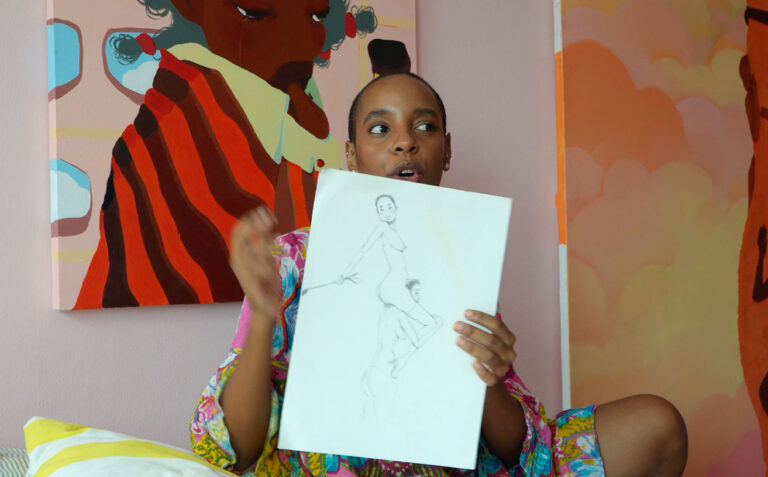 Artist Angie holding a portrait drawing in her studio