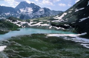Breathtaking alpine lake in Pralognan-la-Vanoise, France with snowy mountains and lush landscape.